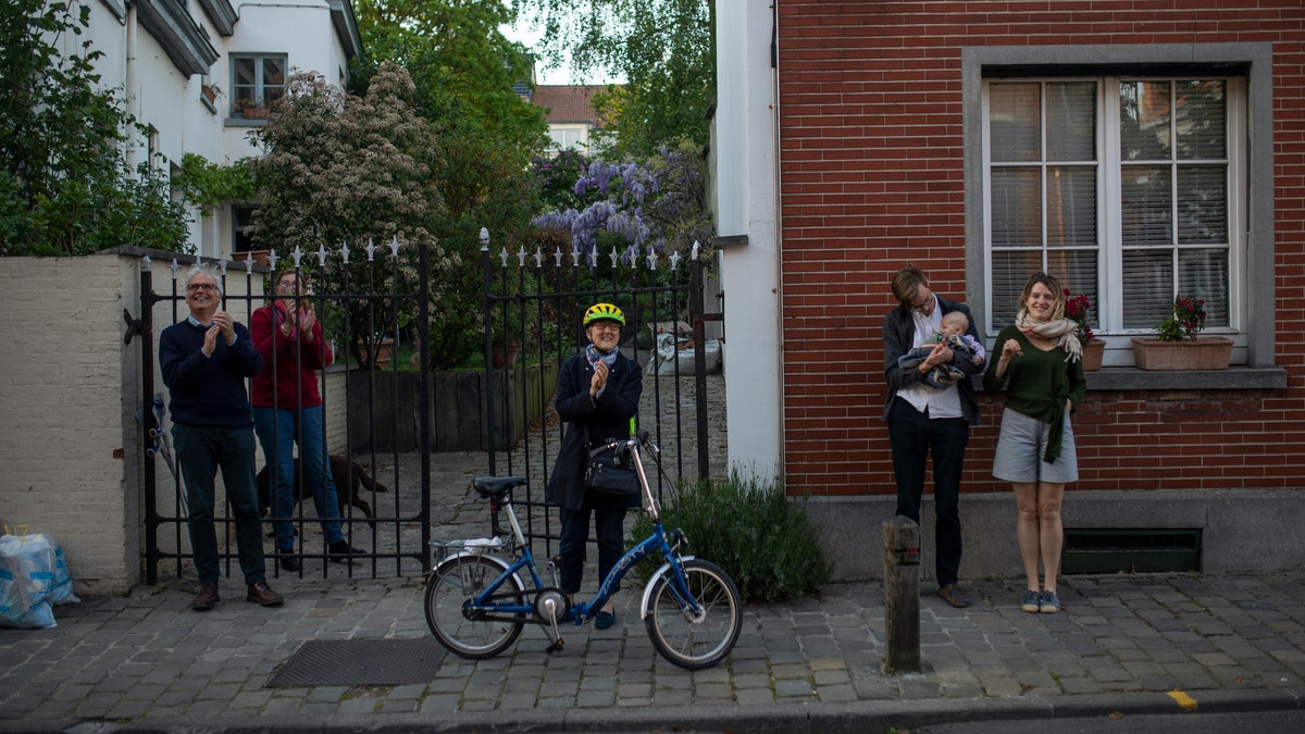 Family members applaud in support of the medical staff who are working in the wake of the COVID-19 outbreak during a partial lockdown against the spread of the coronavirus in Brussels, Tuesday, April 21, 2020. (AP Photo/Francisco Seco)