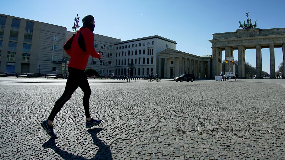 In this March 24, 2020, file photo, a man jogs on the square in front of the Brandenburg Gate in Berlin, Germany. As the restrictions are eased, Chancellor Angela Merkel has pointed to South Korea as an example of how Germany will have to improve measures to “get ahead” of the pandemic with more testing and tracking of cases so that the rate of infections can be slowed. 