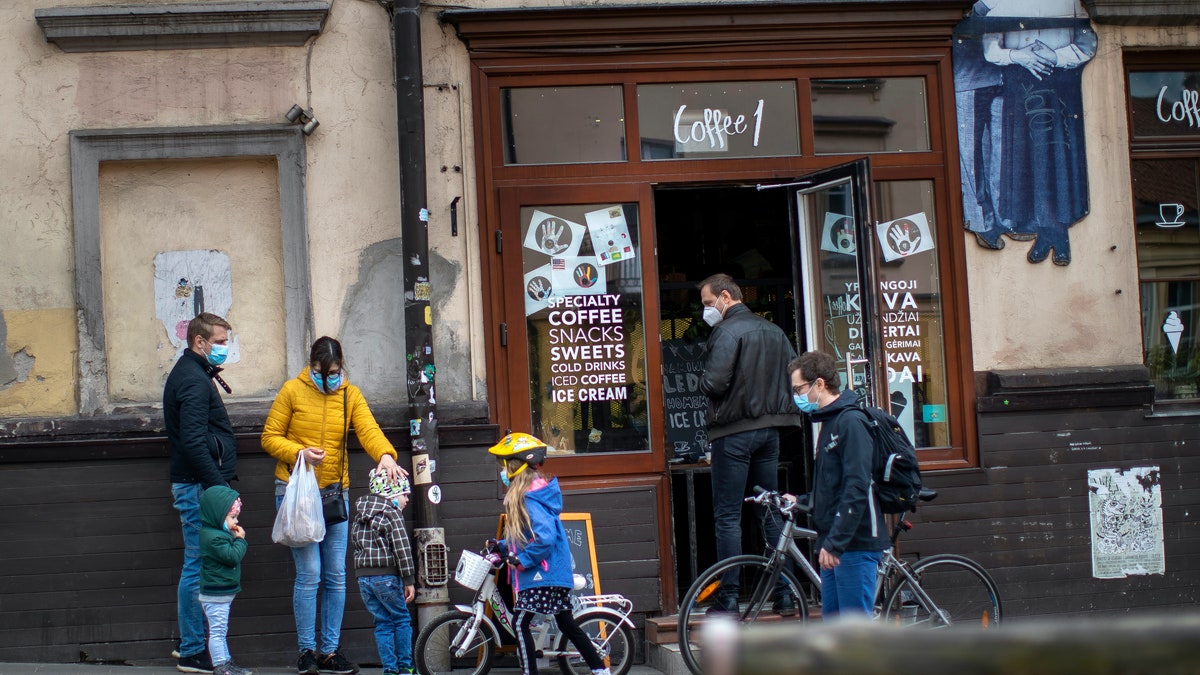 People wearing face masks to protect themselves against the spread of the new coronavirus queue up to buy coffee at a shop in Vilnius, Lithuania, Saturday, April 25, 2020. (AP Photo/Mindaugas Kulbis)
