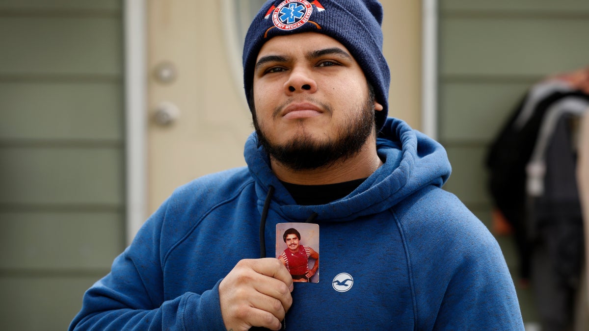 Omar Martinez holds a photo of his father, Jose Gabriel Martinez, as he stands in front of their home, Saturday, April 25, 2020, in West Liberty, Iowa. Martinez's family had been living the American dream after immigrating from Mexico in the 1990s and settling in this small town in eastern Iowa, but their lives fell apart after coronavirus infections spread from his mother to his sister and his father. Now he is planning his father's funeral while hoping his sister recovers in a hospital intensive care unit. He is grateful his mother is better and appreciates the community's support.