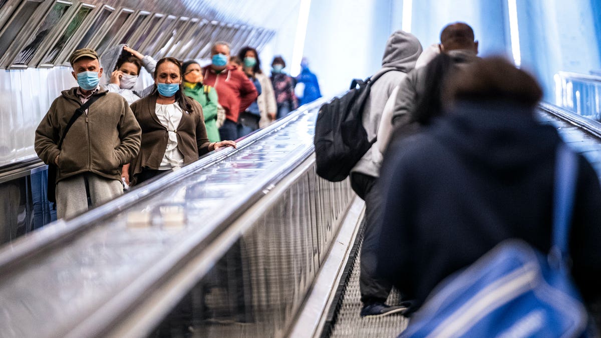 Passengers wear face masks on the escalator of the Szell Kalman station in Budapest, Hungary, Monday, April 27, 2020. From today face masks are mandatory in Budapest when shopping and at public transport due to the coronavirus outbreak. (Zsolt Szigetvary/MTI via AP)