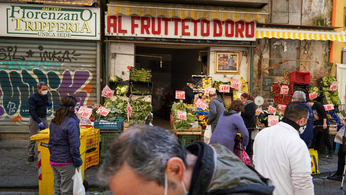 People buy fruit and vegetables at a shop in Naples, Monday, April 27, 2020. Region Campania allowed cafes and pizzerias to reopen for delivery Monday, as Italy it is starting to ease its lockdown after a long precautionary closure due to the coronavirus outbreak. (AP Photo/Andrew Medichini)