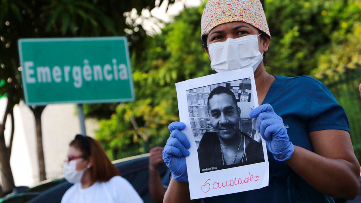 A health worker holds a photo of a person he said was his colleague who died of COVID-19, at a protest outside "Pronto Socorro 28 de Agosto" Hospital in Manaus, Brazil, Monday, April 27, 2020.