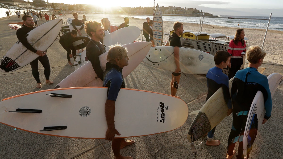 Surfers wait for officials to open Bondi Beach in Sydney, Tuesday, April 28, 2020, as coronavirus pandemic restrictions are eased. The beach is open to swimmers and surfers to exercise only. (AP Photo/Rick Rycroft)