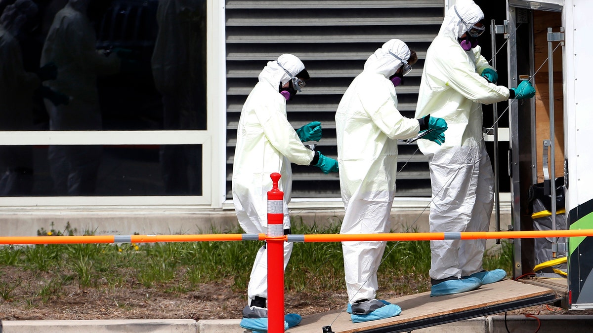 Cleaners unwrap their protective gear as they leave the Soldiers' Home in Holyoke, Mass on March 29. At least 80 residents have died from the coronavirus at the central Massachusetts home for aging veterans, as state and federal officials try to figure out what went wrong in the deadliest outbreak at a long-term care facility in the U.S. (Jessica Rinaldi/The Boston Globe via AP, File)