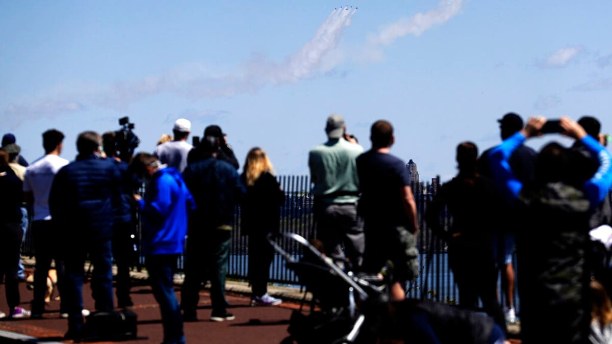 People watch as a formation of the Blue Angels and Thunderbirds flight teams pass in front of the New York City skyline as seen from Weehawken, N.J., Tuesday, April 28, 2020. 