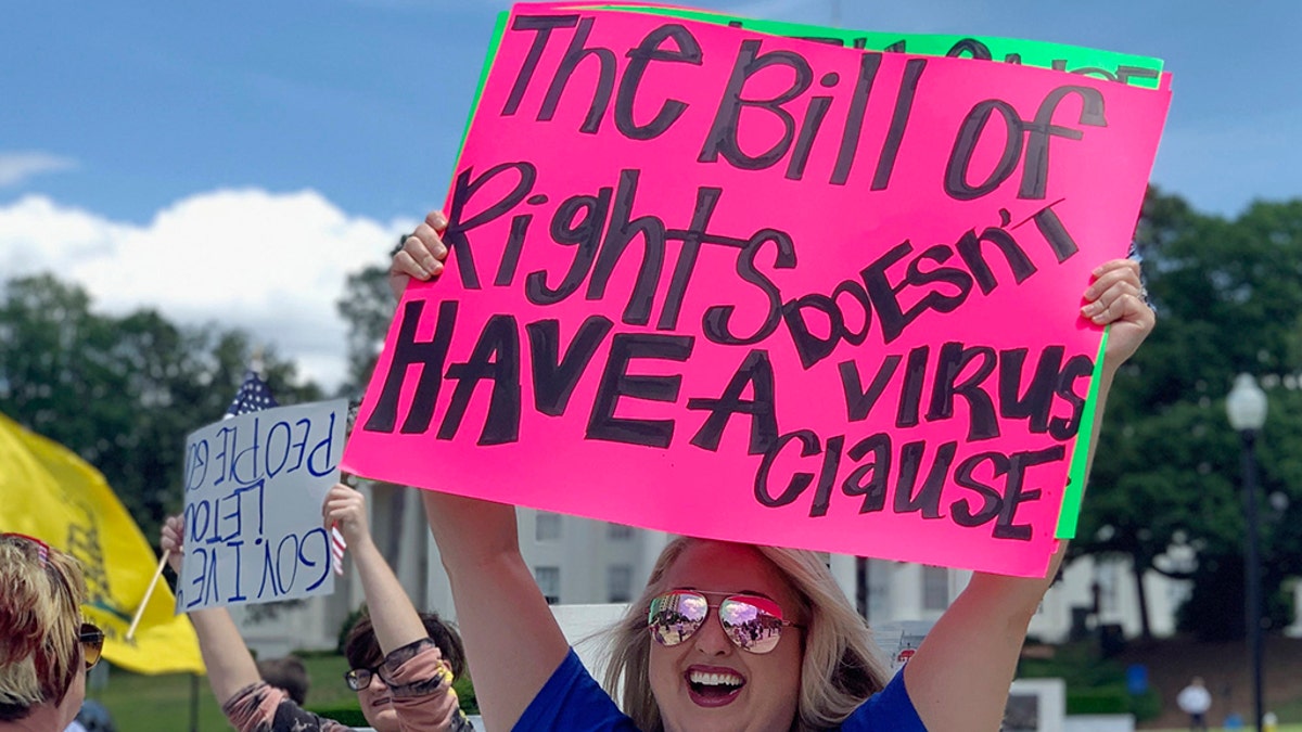Kimmy Tillery, a hairdresser from Tuscaloosa, Ala., holds a sign during a protest to reopen Alabama's economy outside the Capitol in Montgomery, Ala., on Tuesday, April 21, 2020. (AP Photo/Kim Chandler)