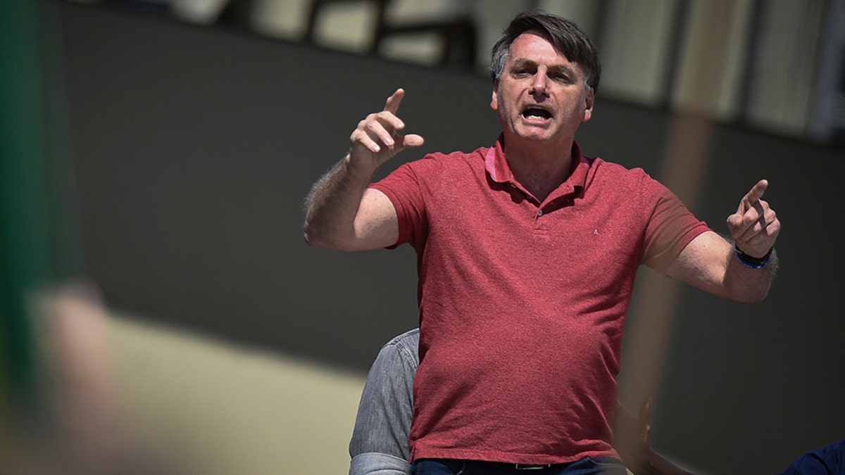Brazil's President Jair Bolsonaro speaks to supporters during a protest asking for military intervention in front the army's headquarters during the new coronavirus pandemic, in Brasilia, Brazil, Sunday, April 19, 2020. Bolsonaro came out in support of a small protest Sunday that defended military intervention, infringing his own ministry's recommendations to maintain social distancing and prompting fierce critics. (AP Photo/Andre Borges)