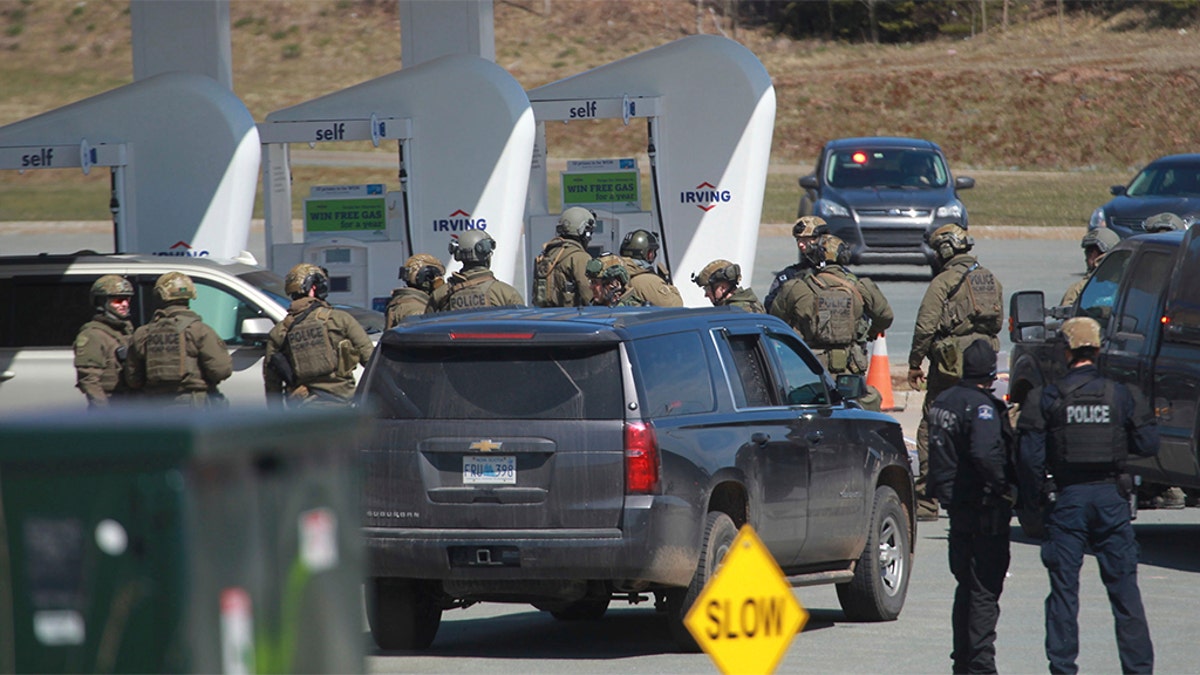 Royal Canadian Mounted Police officers prepare to take a person into custody at a gas station in Enfield, Nova Scotia on Sunday April 19, 2020. A suspect in an active shooter investigation is in custody in Nova Scotia, with police saying several people were harmed before a man wearing police clothing was arrested. (Tim Krochak/The Canadian Press via AP)