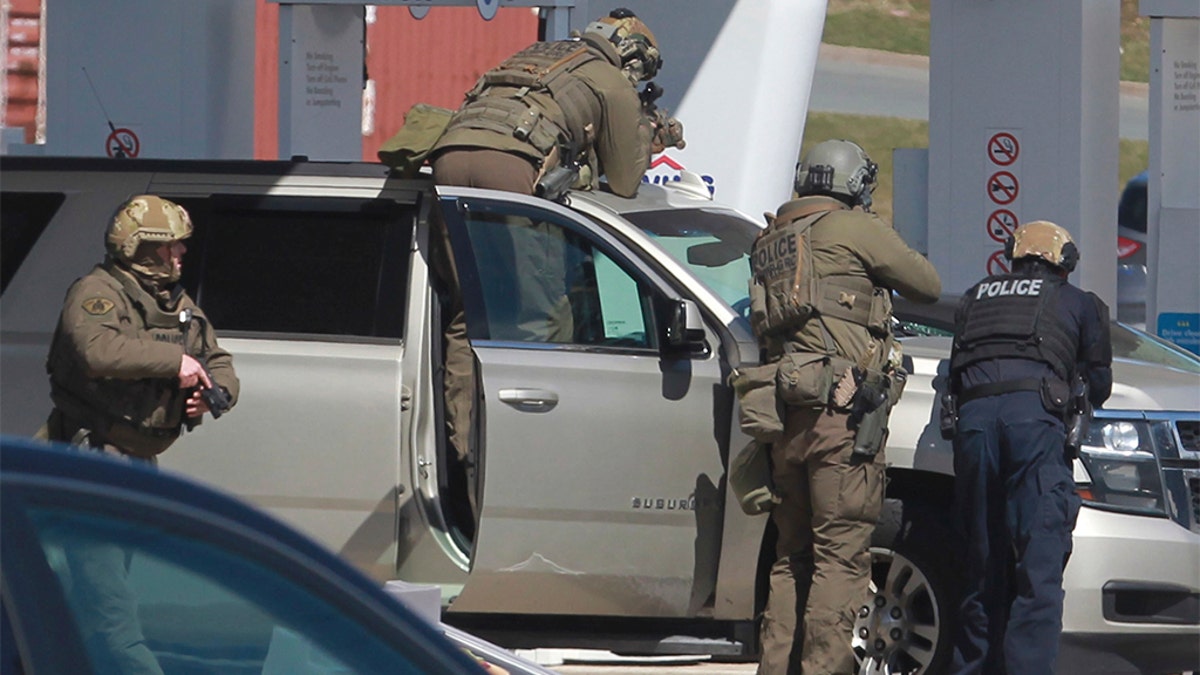 Royal Canadian Mounted Police officers prepare to take a suspect into custody at a gas station in Enfield, Nova Scotia on Sunday, April 19, 2020. (Tim Krochak/The Canadian Press via AP)