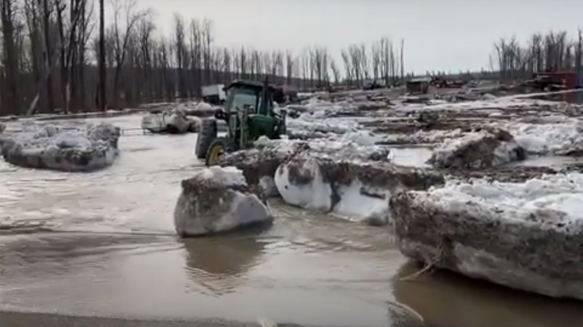 Chunks of ice and water can be seen flowing onto a street near Fort McMurray, Alberta after an ice jam caused major flooding in the region.