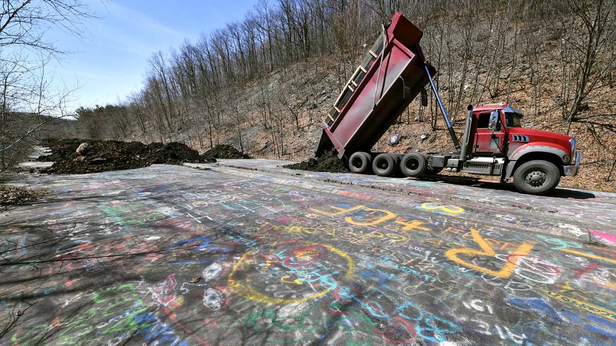A dump truck with Fox Coal Company dumps a load of dirt onto of the Graffiti Highway outside of Centralia, PA, Monday, April 6, 2020, while working to cover up the tourist denotation.