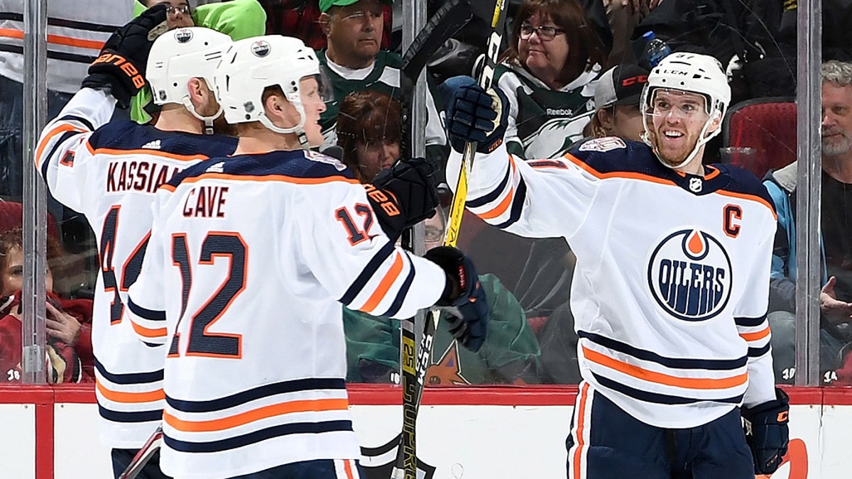 Connor McDavid #97 of the Edmonton Oilers celebrates with teammates Zack Kassian #44 and Colby Cave #12 after scoring the game-winning goal in overtime against the Arizona Coyotes at Gila River Arena on March 16, 2019 in Glendale, Arizona. The Oilers defeated the Coyotes 3-2. (Photo by Norm Hall/NHLI via Getty Images)