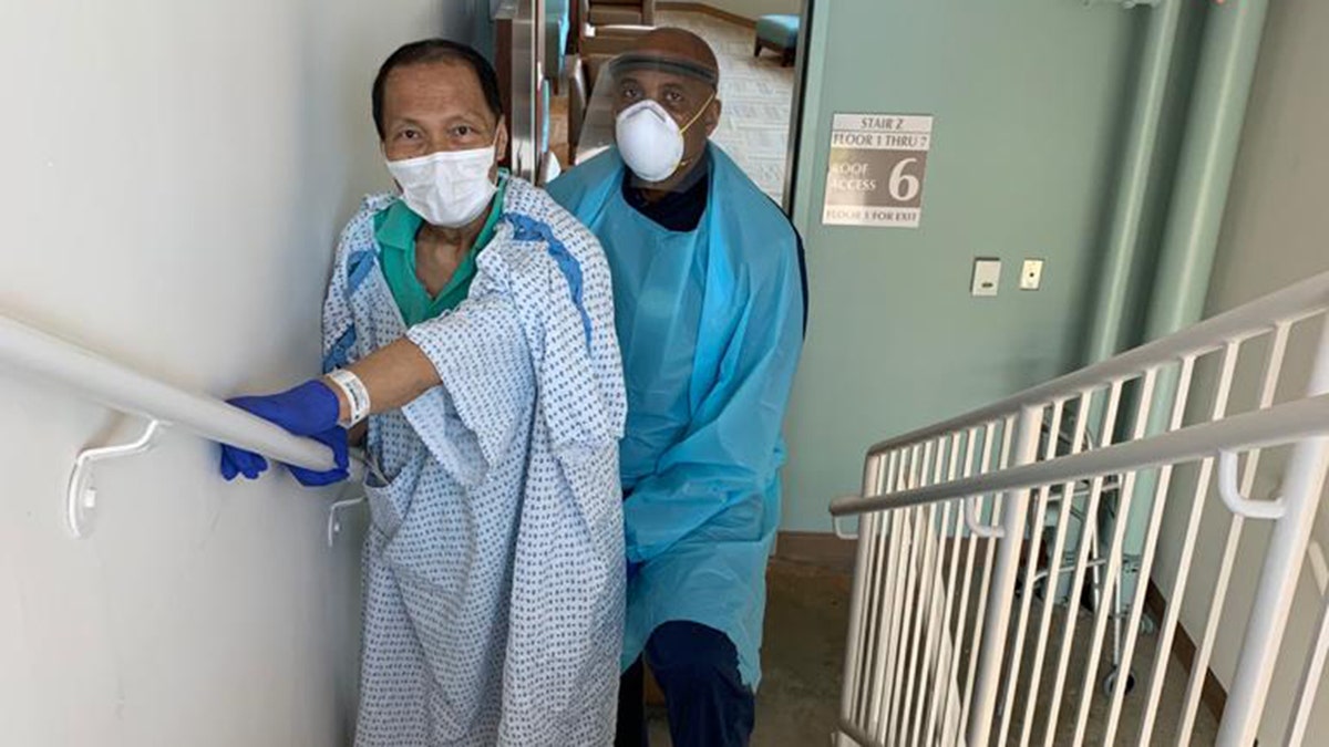 Dr. Bulauitan working with his physical therapist. After extubation he could not lift his arms or legs off the bed. He was told if he could walk up 4 steps, then he could be discharged to his son's home. Within five days, Bulauitan was able to walk!