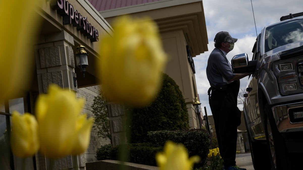 A worker delivers alcohol to a customer for curbside pickup outside a state liquor store in Fox Chapel, Pa. on April 21. (Michael Swensen/Bloomberg via Getty Images)
