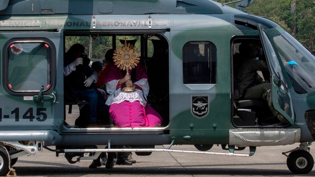 Panama's Archbishop Jose Domingo Ulloa holds the Blessed Sacrament as he sits on a helicopter at Howard Air Force Base in Panama City on April 5, 2020 before a flight over the capital and surrounding areas to "protect the country from disease" amid fears of the spread of the novel coronavirus, COVID-19. (Photo by LUIS ACOSTA/AFP via Getty Images)