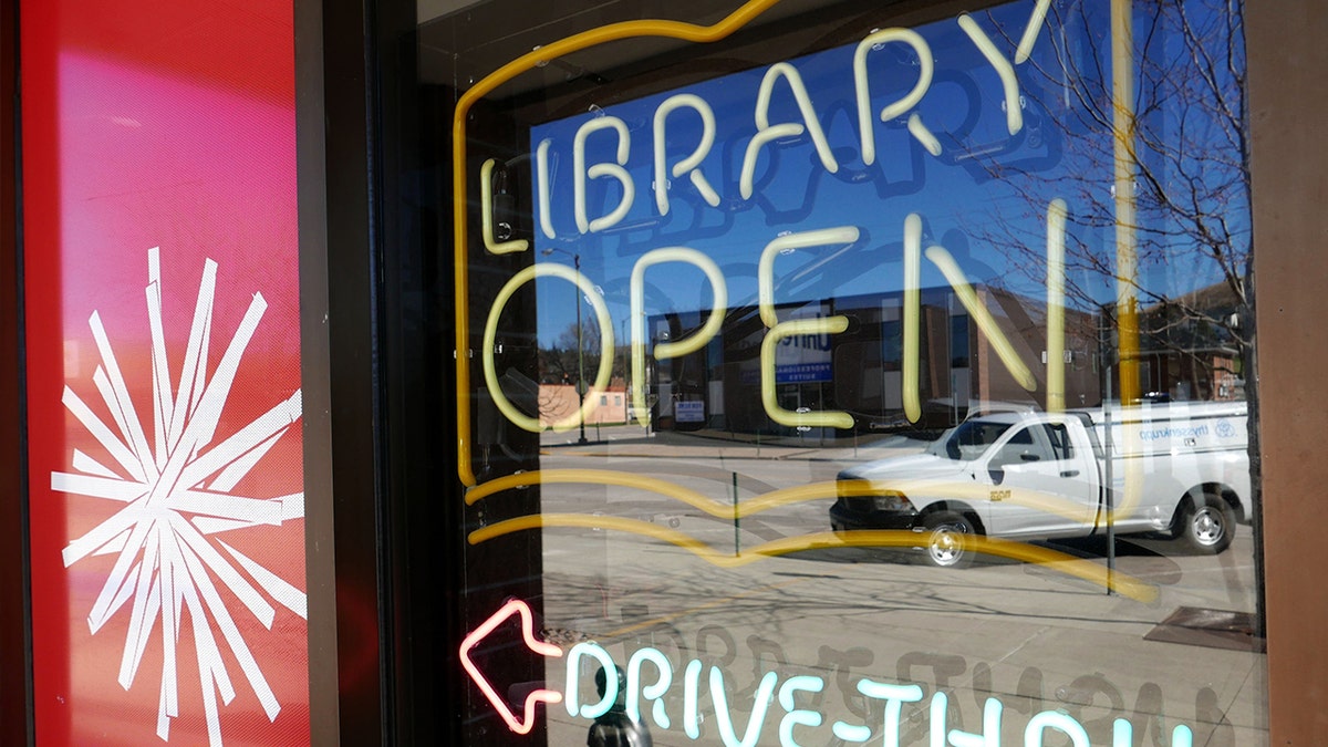 A library is shown with an "open" sign and directions for "drive-thru" service.