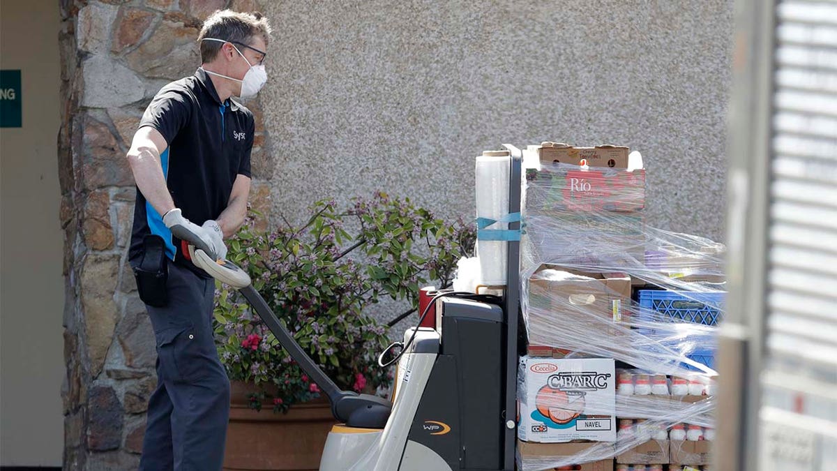 A worker wearing a mask delivers food to the Life Care Center in Kirkland, Wash. Federal authorities on Wednesday, April 1, 2020, proposed a fine of more than $600,000 for the Seattle-area nursing home connected to at least 40 deaths from the new coronavirus. 