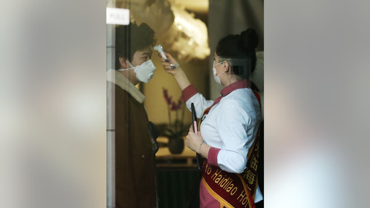 A member of the staff at a restaurant in London is photographed taking a customer's temperature before allowing him to enter, a precaution adopted by some chains the United States, though usually for the waitstaff.