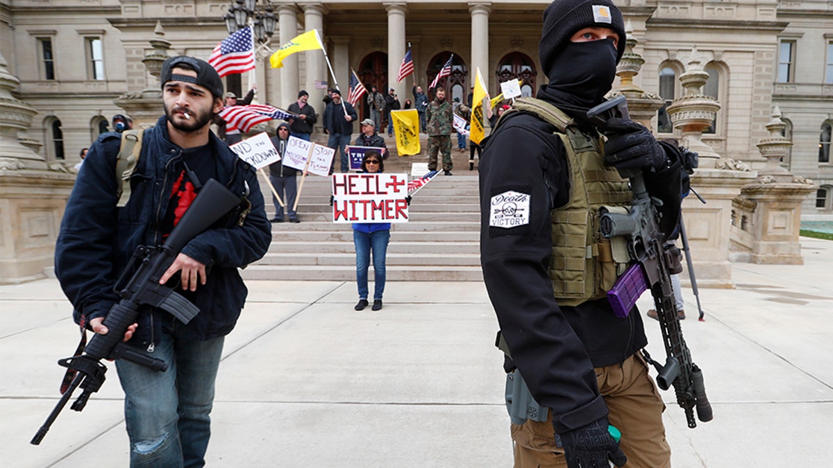Protesters carry rifles near the steps of the Michigan State Capitol building in Lansing, Mich., Wednesday, April 15, 2020. Flag-waving, honking protesters drove past the Michigan Capitol on Wednesday to show their displeasure with Gov. Gretchen Whitmer's orders to keep people at home and businesses locked during the new coronavirus COVID-19 outbreak.