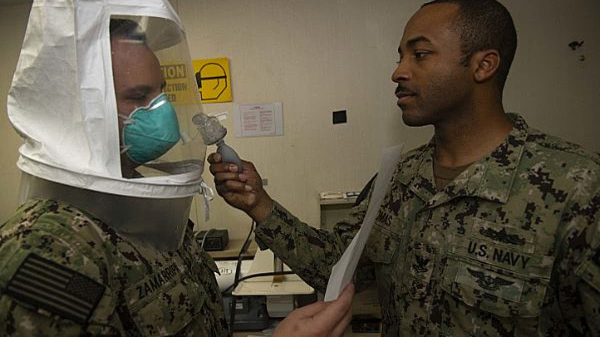 Hospital Corpsman 2nd Class Vernon Thomas, right, tests for a proper seal on respiratory protective equipment by administering a saccharine mist for Hospitalman David Zamarripa to detect during a fit test aboard the Military Sealift Command hospital ship USNS Comfort while the ship is in New York City in support of the nation’s COVID-19 response efforts.