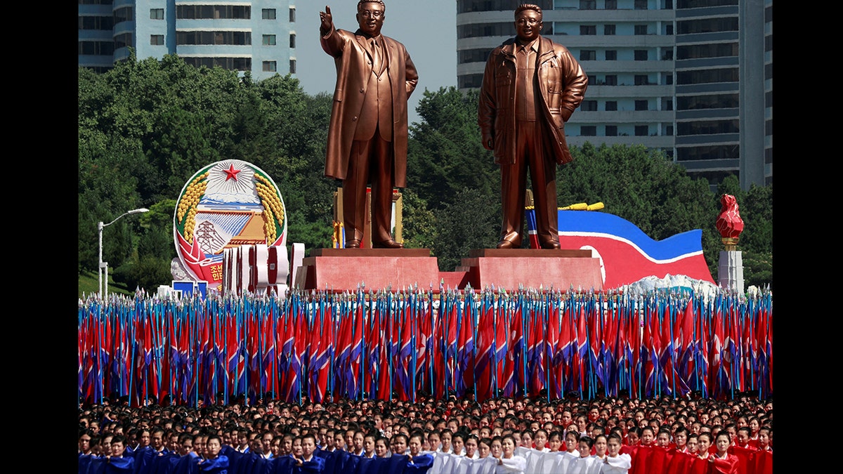 People carry flags in front of statues of North Korea founder Kim Il Sung (L) and late leader Kim Jong Il during a military parade marking the 70th anniversary of North Korea's foundation in Pyongyang. (REUTERS/Danish Siddiqui)