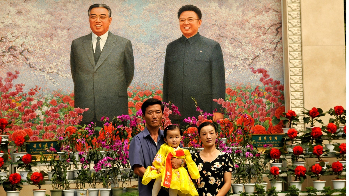 North Koreans pose for a family portrait in front of portraits of President Kim Il Sung (L) and his son Kim Jong Il. (Photo by Alain Nogues/Corbis via Getty Images)