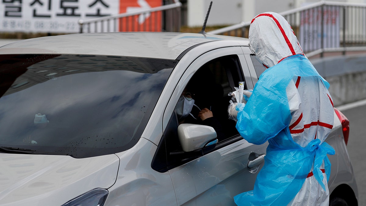  A medical staff member in protective gear prepares to take samples from a visitor at a 'drive-thru' testing center for the novel coronavirus disease of COVID-19 in Yeungnam University Medical Center in Daegu, South Korea on March 3. (REUTERS/Kim Kyung-Hoon)