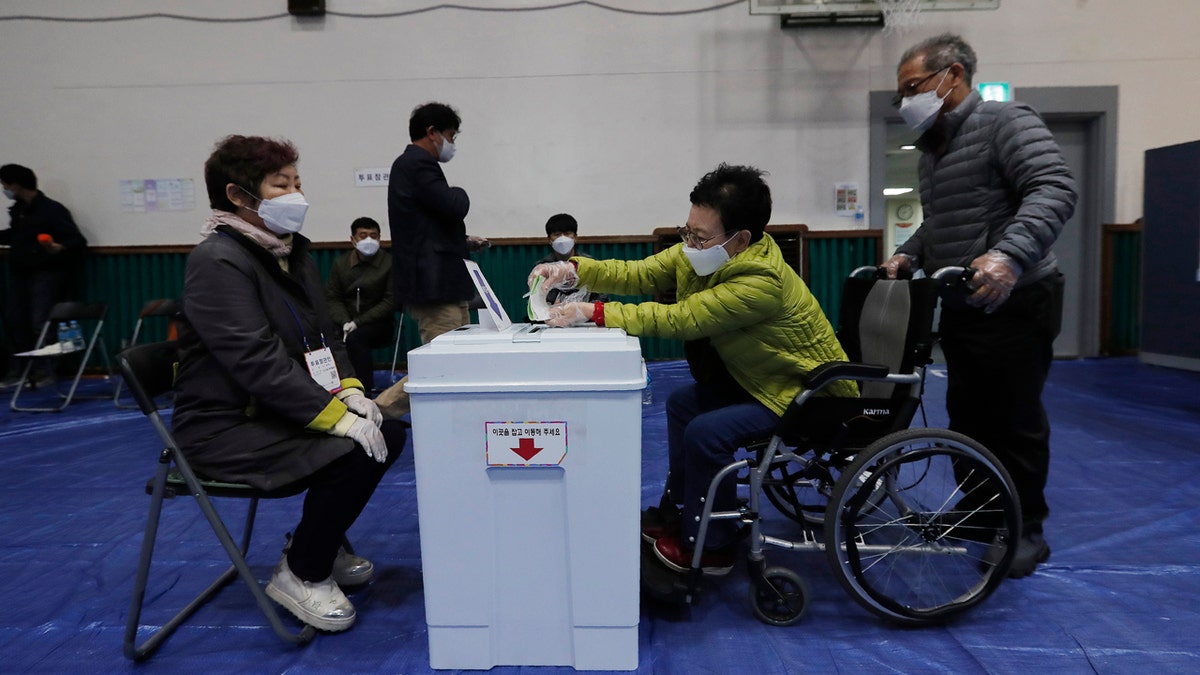 A woman wearing a face mask to help protect against the spread of the new coronavirus casts her vote for the parliamentary election at a polling station in Seoul, South Korea, Wednesday, April 15, 2020.