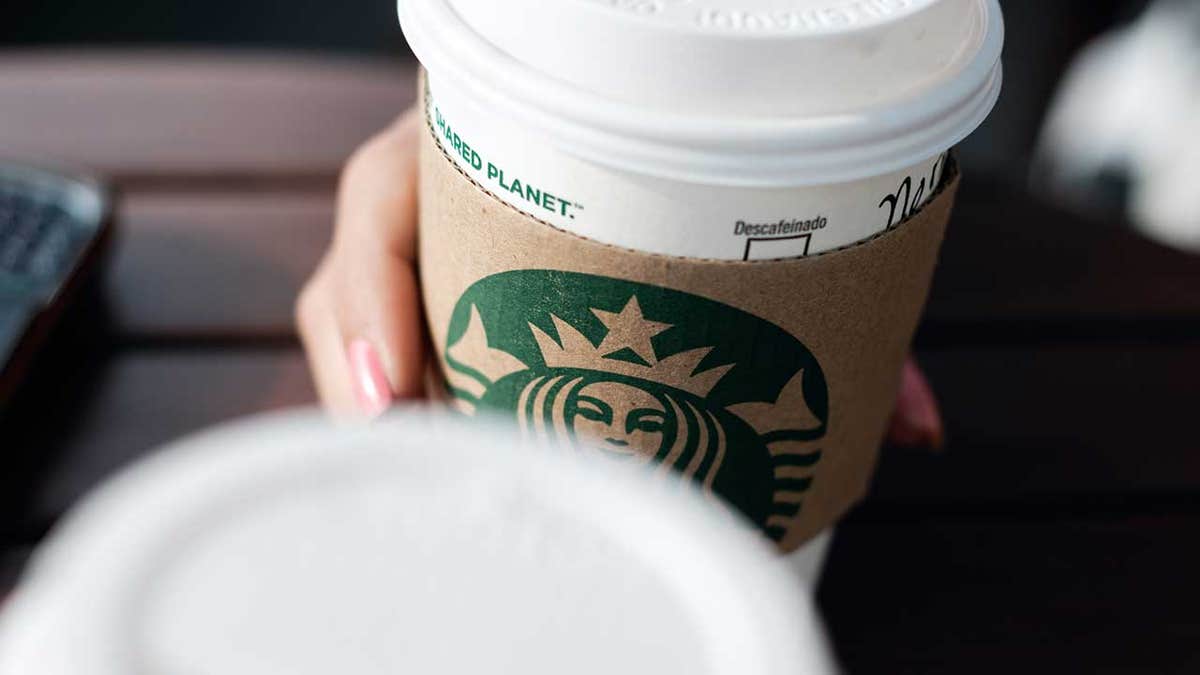 A woman holds a Starbucks coffee cup.