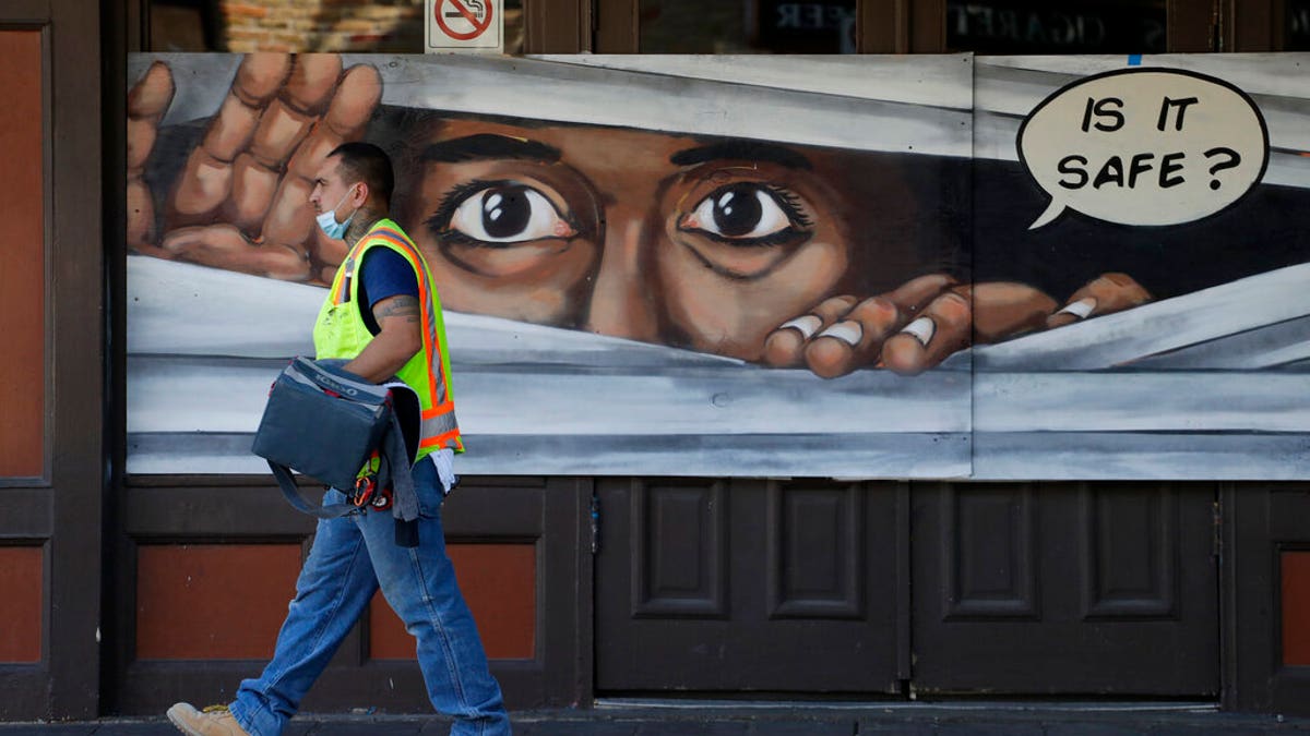 A construction worker walks past a mural painted on a boarded up business that is temporarily closed due to the COVID-19 pandemic, in Austin, Texas. Texas Gov. Greg Abbott announced he is relaxing some restrictions that have been imposed on some businesses. (AP Photo/Eric Gay)