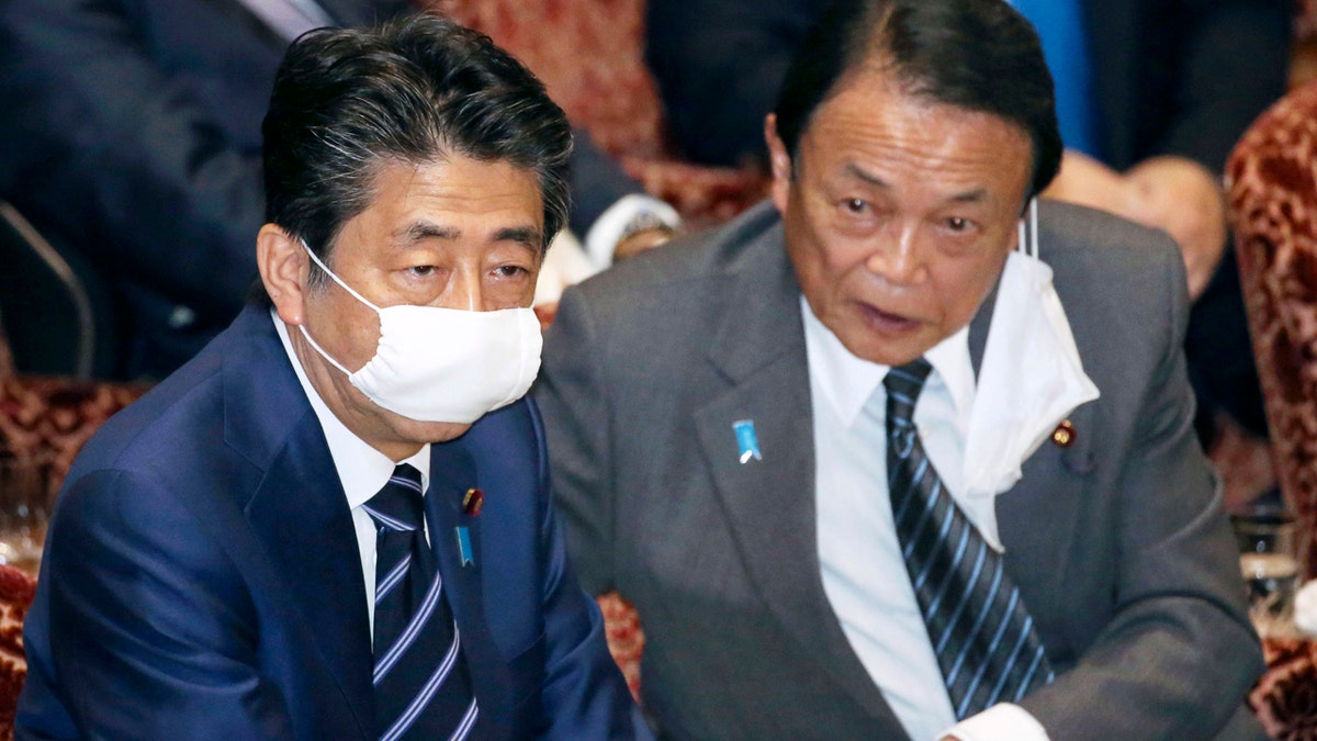 Japanese Prime Minister Shinzo Abe, left, and Financial Minister Taro Aso, wear face masks as a safety precaution against the new coronavirus attend a session of the parliament's upper house in Tokyo Wednesday.