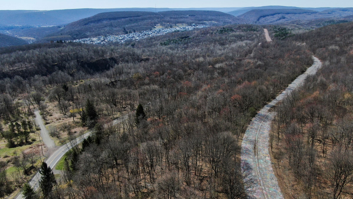 The landowner has started to cover the Graffiti Highway, former Route 61, right, with dirt on April 6 near Centralia, Pa. The Byrnsville Road, left, bypasses the abandoned section of Route 61 and the borough of Ashland can be seen in the distance.