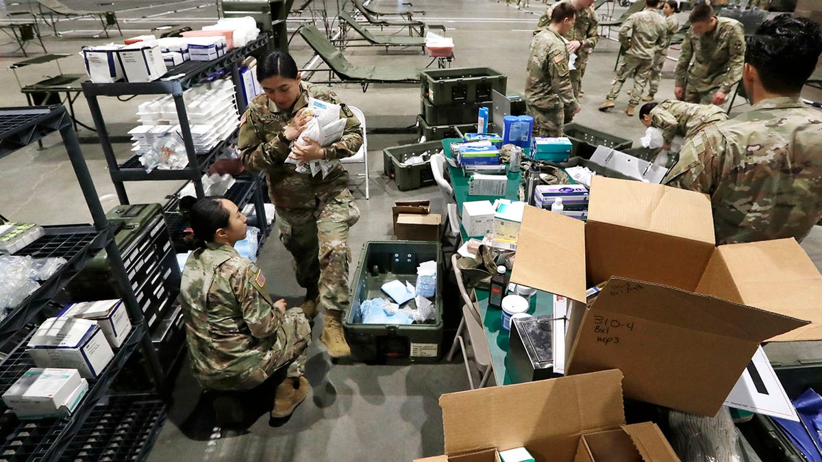 Soldiers unload supplies as they work to set up a field hospital inside CenturyLink Field Event Center on Tuesday. (AP Photo/Elaine Thompson)
