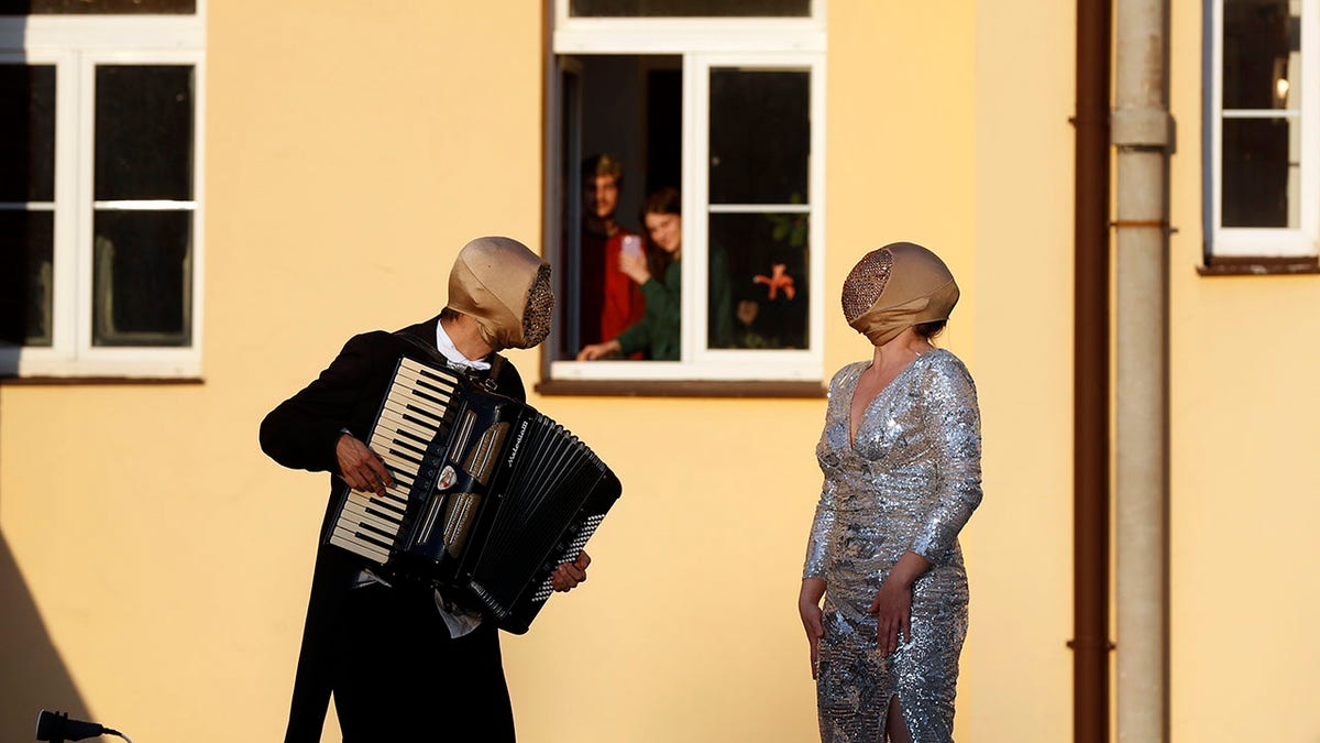 Street musicians entertain residents as people stay in their houses to counter the spread of coronavirus, in Prague, Czech Republic, Tuesday, April 7, 2020. (AP Photo/Petr David Josek)