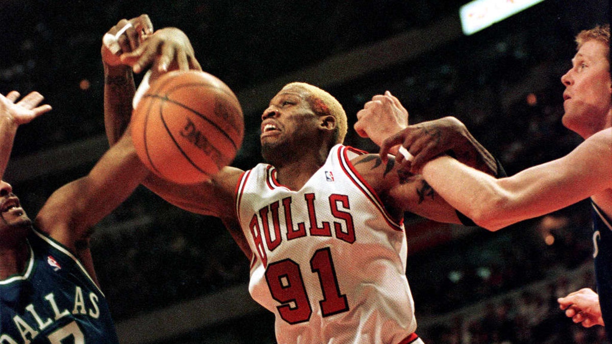 Chicago Bulls forward Dennis Rodman (center) fights for a rebound with Dallas Mavericks center Shawn Bradley (right) and forward Dennis Scott (left) during the fourth quarter, Dec. 29, 1997, at the United Center, in Chicago, Illinois.