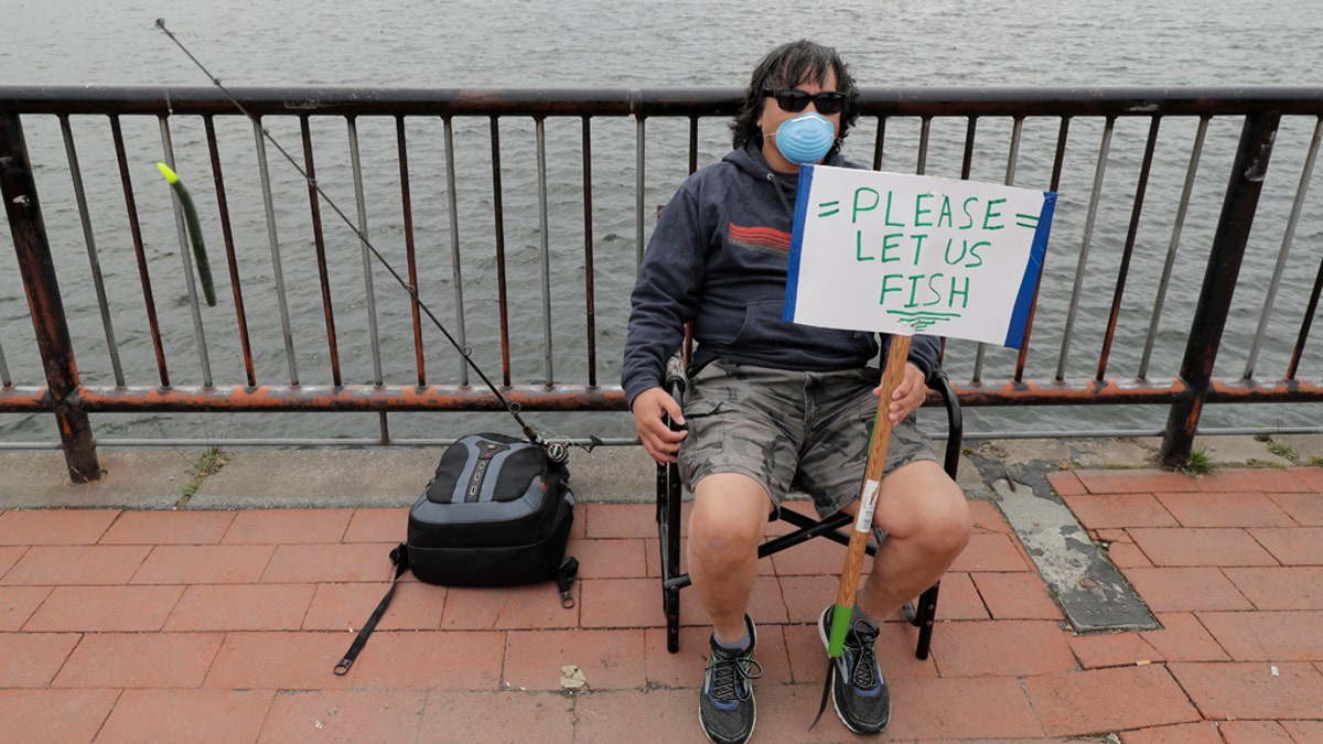 Ray Kawabata holds a sign that reads "Please Let Us Fish" at Gas Works Park in Seattle on April 26, during a protest against Washington state's current ban on fishing due to stay-at-home orders implemented to prevent the spread of the coronavirus. (AP Photo/Ted S. Warren)