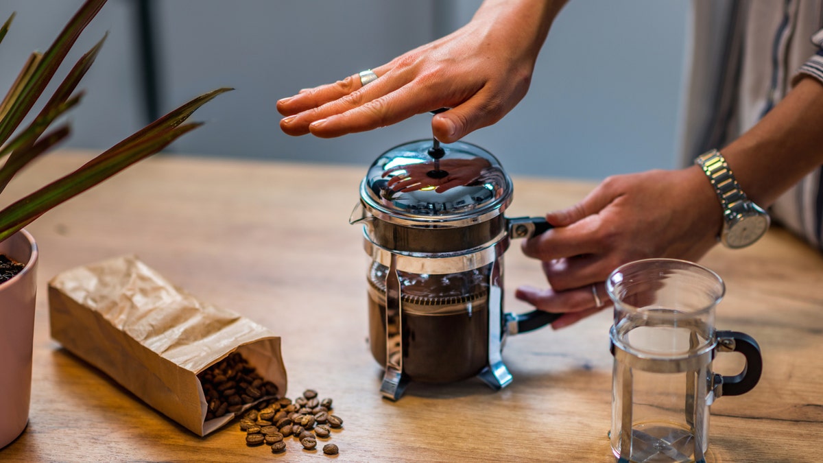 French press in use by person making coffee