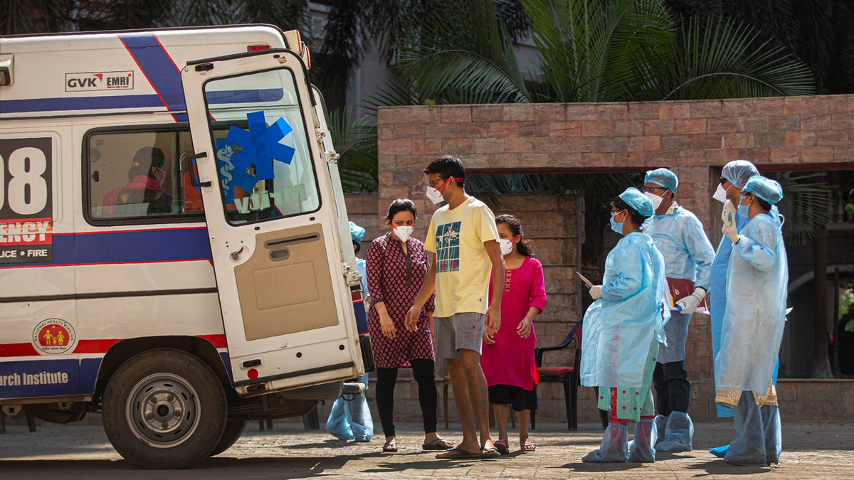 People from an apartment complex board an ambulance to be taken to a hospital for quarantine after a person was found to be COVID-19 positive, in Gauhati, India.