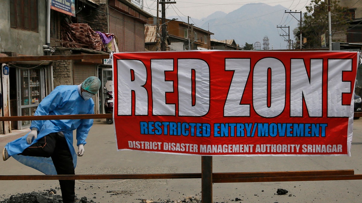 A Kashmiri man wearing protective gear crosses a barricade in an area declared as red zone by the government during lockdown in Srinagar, Indian controlled Kashmir, April 14.