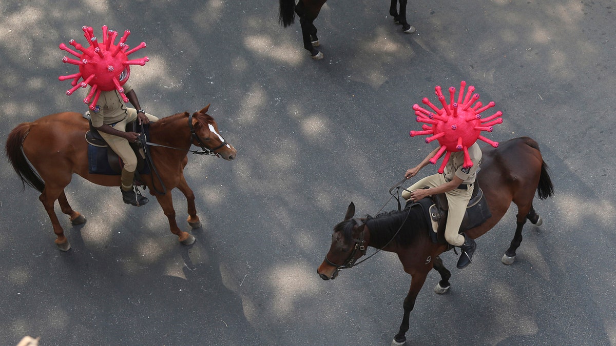 Indian policemen wearing virus-themed helmets ride on horses during an awareness rally aimed at preventing the spread of new coronavirus in Hyderabad, India, on April 2, 2020.