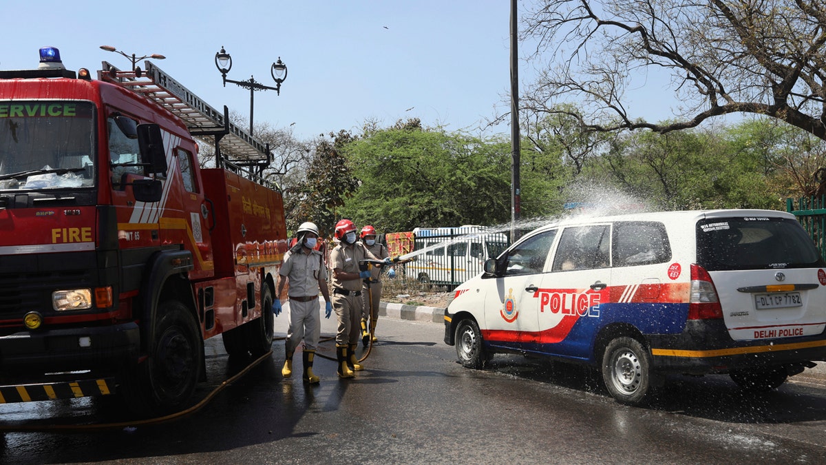 Delhi fire officers spray disinfectant on a police vehicle during a 21 day lockdown to control the spread of coronavirus in New Delhi, India, Thursday, April 2, 2020.
