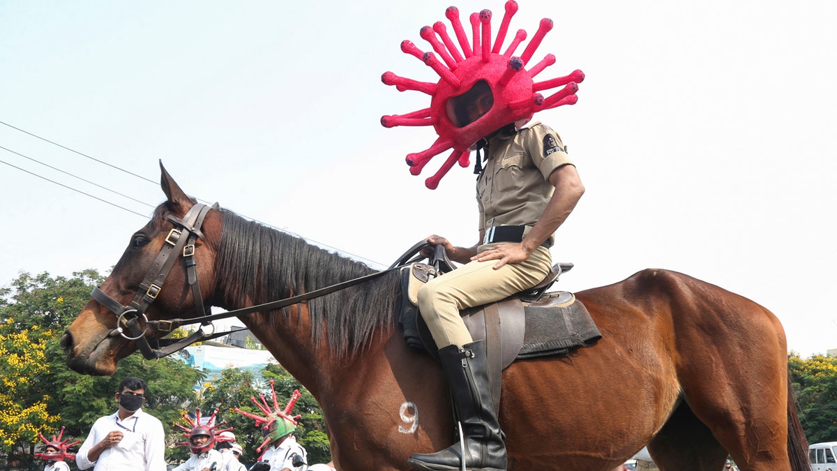 An Indian policeman wearing a virus themed helmet rides on a horse during an awareness rally aimed at preventing the spread of new coronavirus in Hyderabad, India, Thursday, April 2, 2020.
