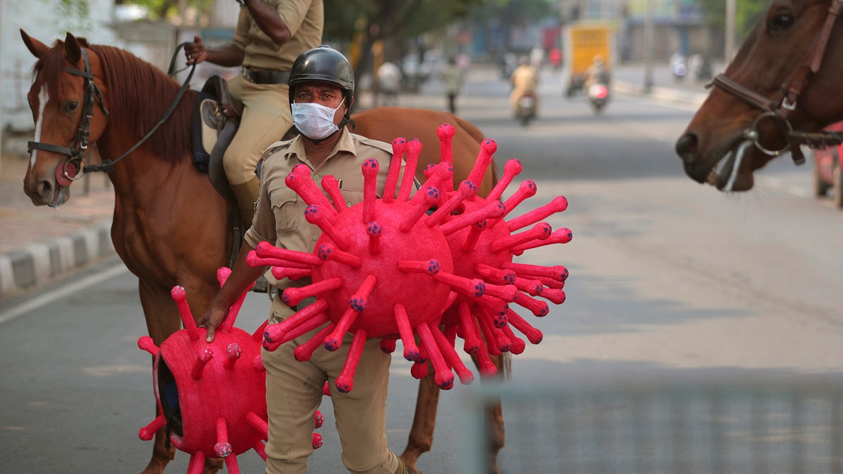 An Indian policemen carries virus themed helmets during an awareness rally aimed at preventing the spread of new coronavirus in Hyderabad, India, Thursday, April 2, 2020.
