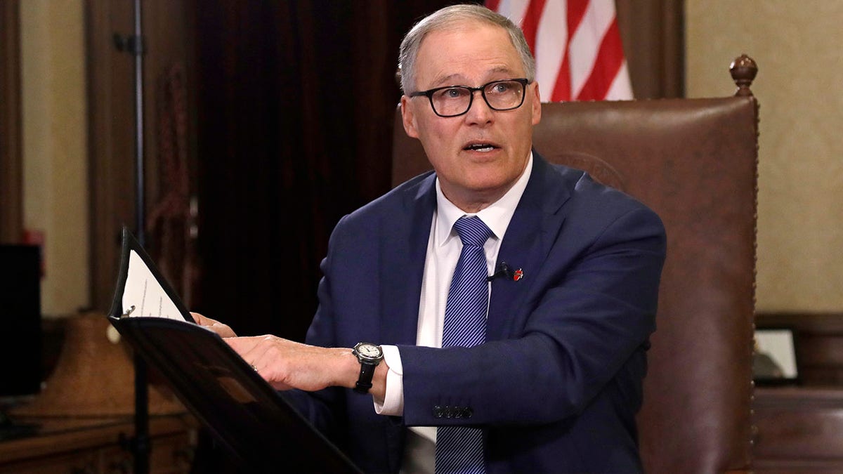 Gov. Jay Inslee turns to staff members as he prepares to speak about additional plans to slow the spread of coronavirus before a televised address from his office on March 23 in Olympia, Wash. (AP Photo/Elaine Thompson)