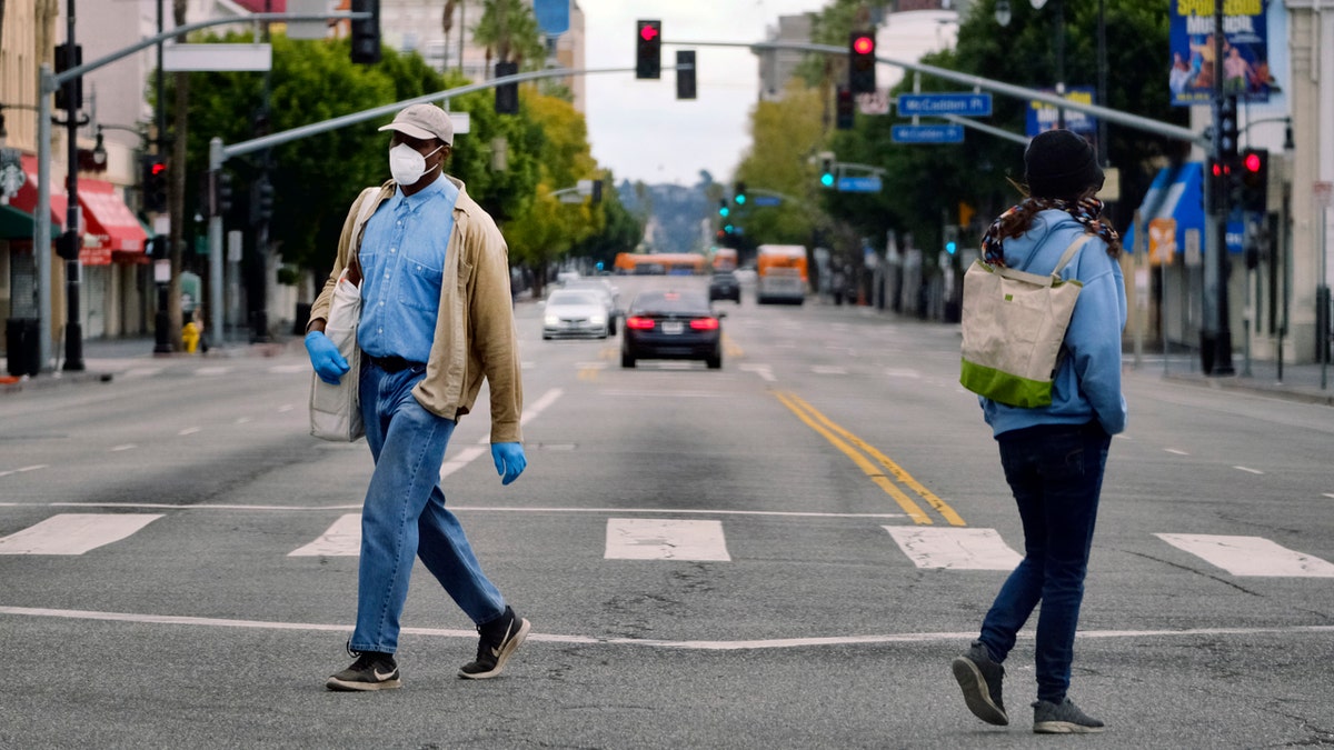 Pedestrians wearing protective masks during the coronavirus outbreak walk in the Hollywood section of Los Angeles.