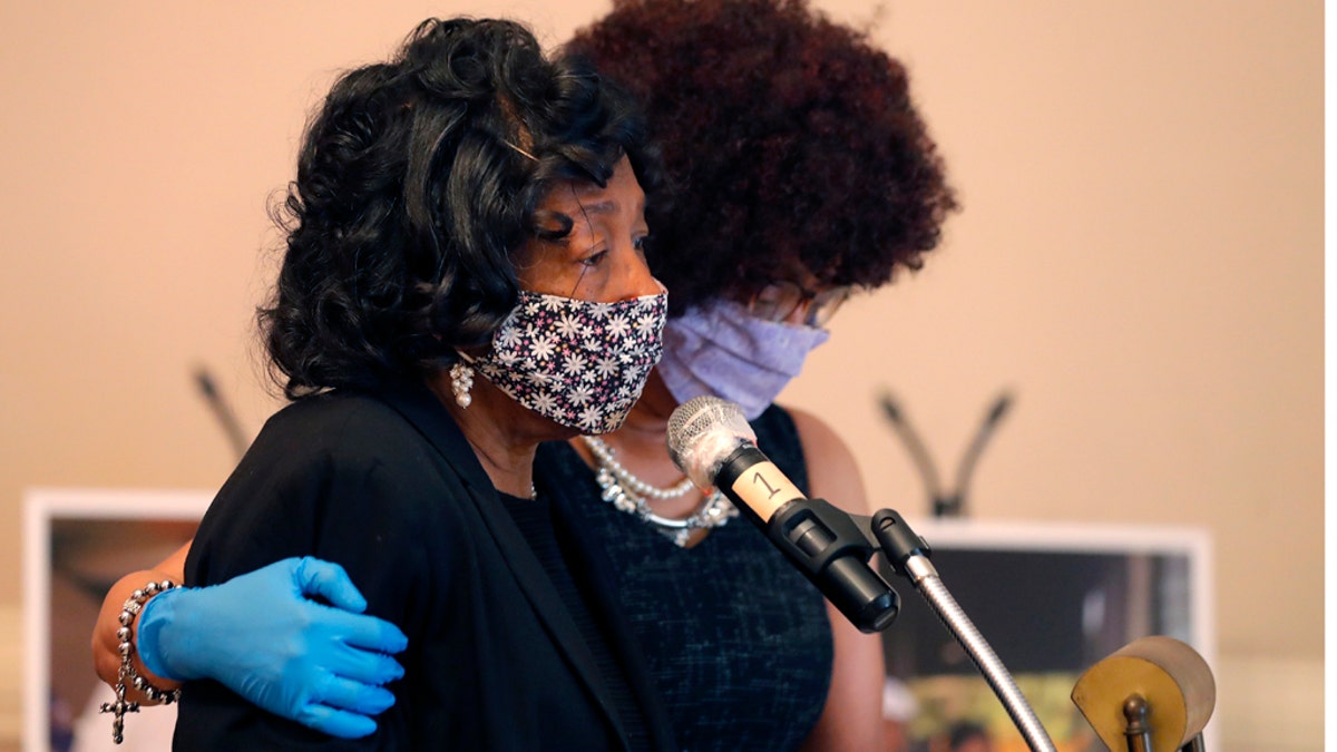 Lillian P. Hammond, foreground, is comforted by her sister-in-law Lori Adams, as she speaks at the funeral funeral for her husband Larry Hammond, who died from the coronavirus, in New Orleans, April 22. (AP Photo/Gerald Herbert)