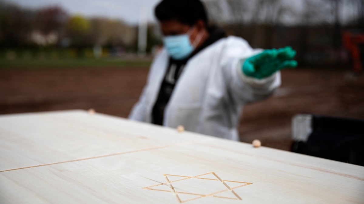 Gravedigger Thomas Cortez directs his coworker where to stop the pickup truck carrying a casket as it's brought to a plot for burial at Hebrew Free Burial Association's Mount Richmond Cemetery in the Staten Island borough of New York, April 8. (AP Photo/David Goldman)
