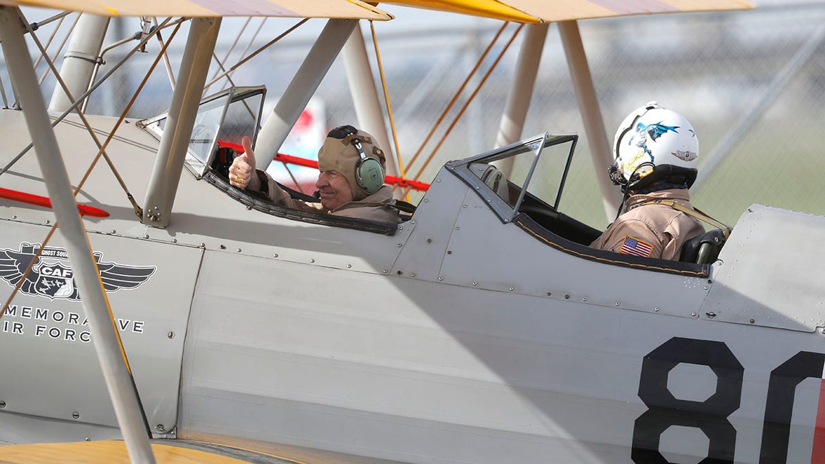 Archbishop Gregory Aymond, left, gives a thumbs-up as he gets set to ride in a World War II-era Stearman PT-17 biplane over the city on Friday. (AP Photo/Gerald Herbert)
