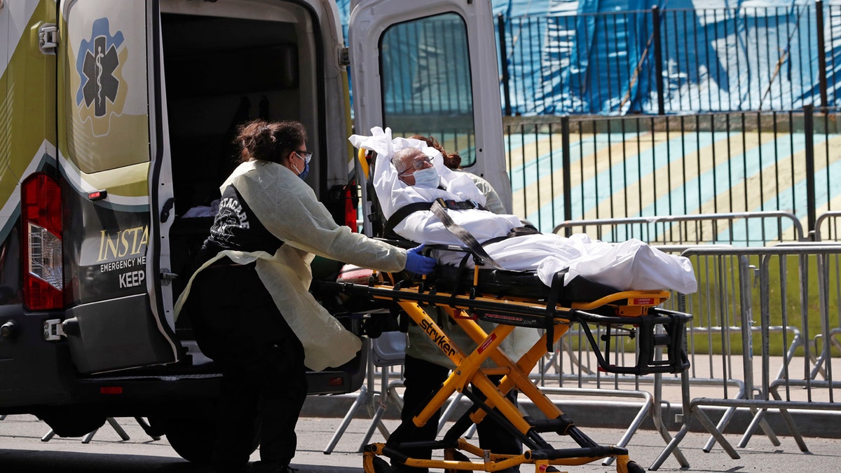 A patient is transferred from Elmhurst Hospital Center to a waiting ambulance during the current coronavirus outbreak, Tuesday, April 7, 2020, in New York.